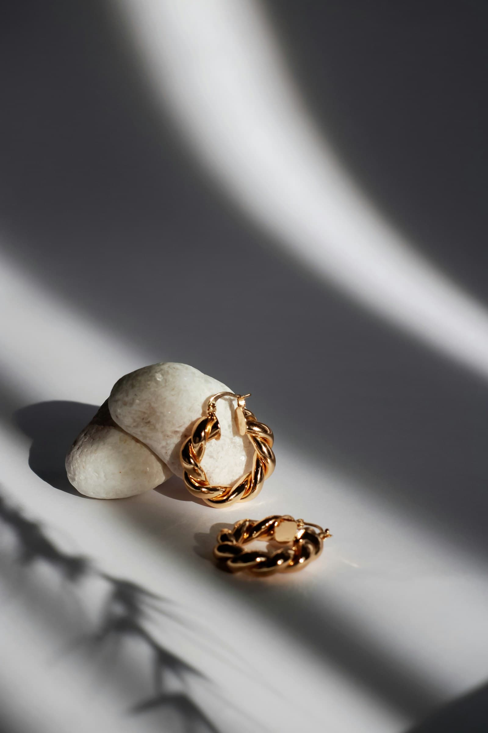 A fine gold chain arranged over a smooth stone.