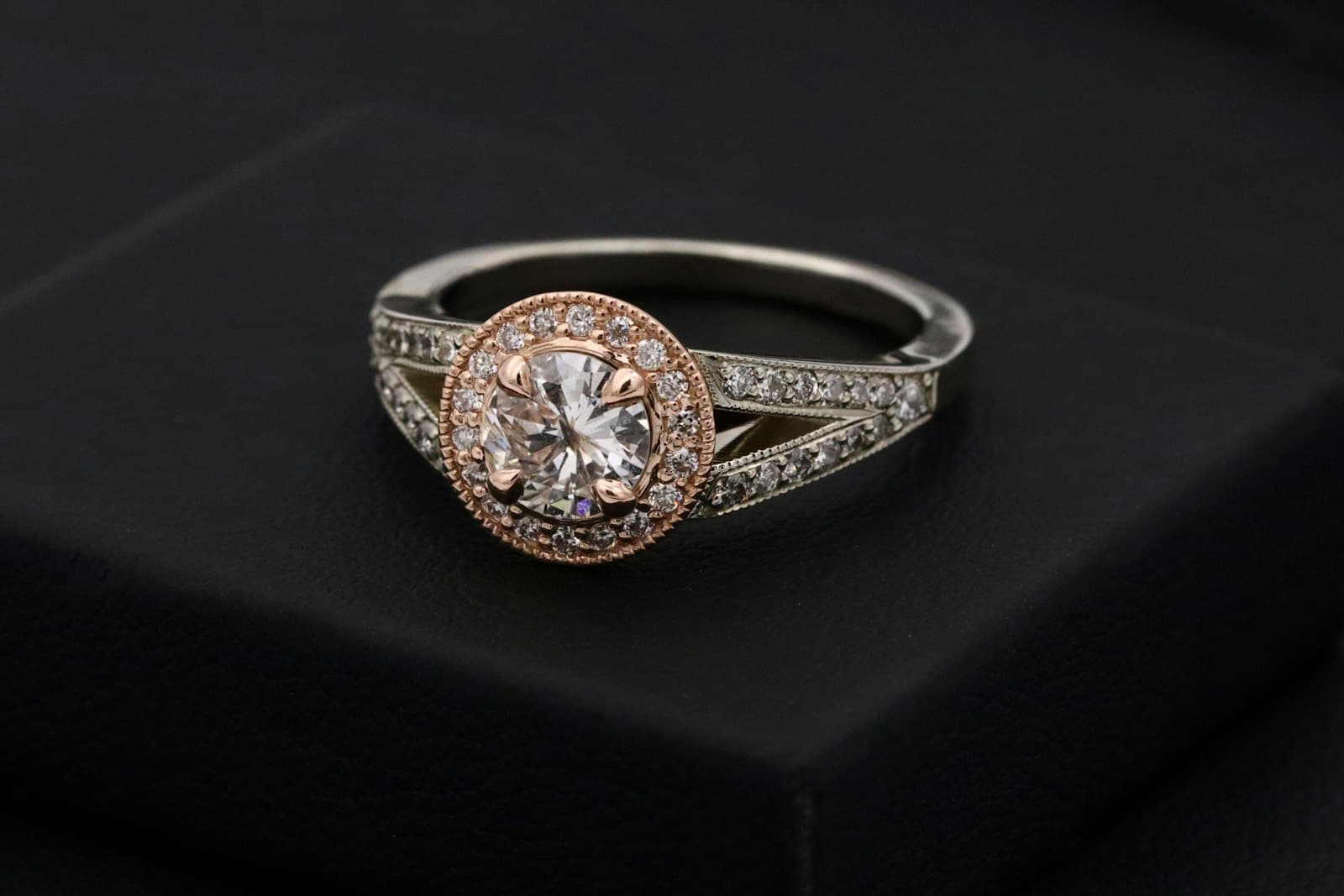 A brilliant-cut solitaire ring on a dark presentation box.